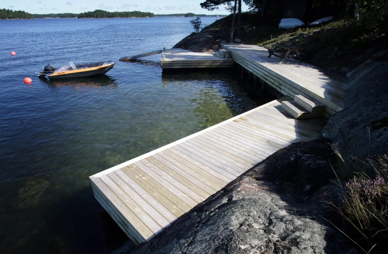 En träbrygga med tillhörande landgång som vilar stadigt mot en stenig strand.